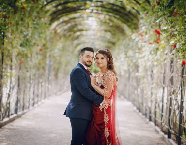 Beautiful woman in a long red dress walks around the city with her husband in a blue suit and with a beard